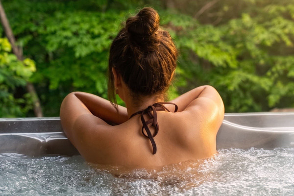 Hot tub at dusk off the master suite, private forest backdrop, heated year-round.