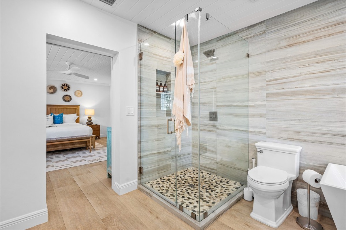 Step into a private spa-like escape with a glass-enclosed shower, stone details, and seamless flow from the bedroom.