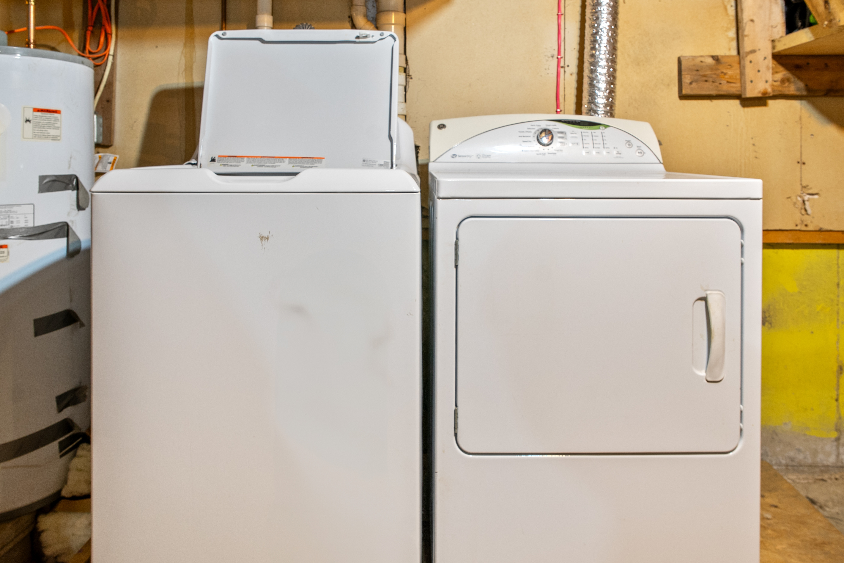 Keep your wardrobe fresh during extended stays with the convenient on-site laundry setup. This straight-on perspective displays the heavy-duty top-loading washing machine and matching front-loading electric clothes dryer ready for guest use.
