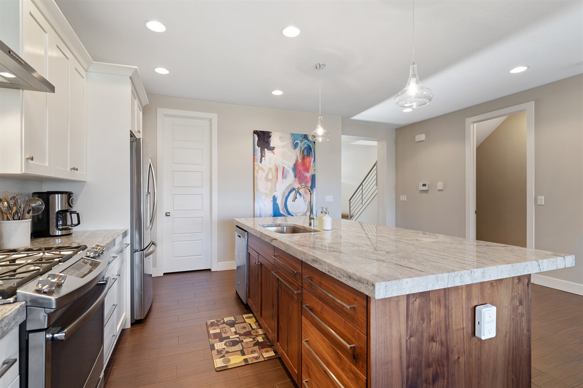 Large kitchen island, gas stove, modern appliances, and ample prep space.