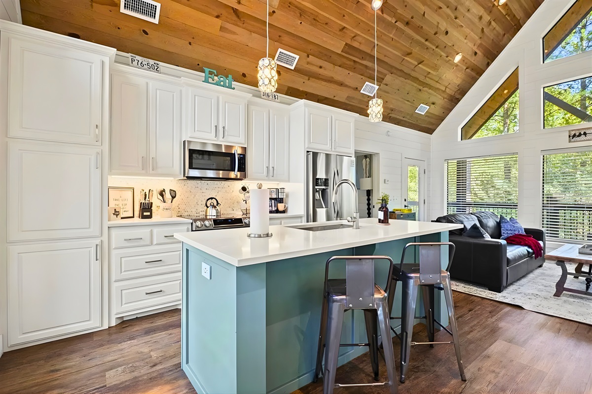 Bright, open, and made for gathering, this kitchen features a spacious island with seating, modern appliances, and warm wood ceilings that make it feel both stylish and inviting.