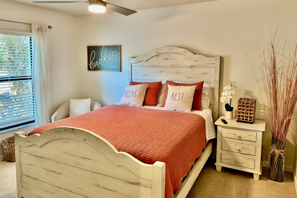 Second bedroom—queen bed, TV, accent chair.