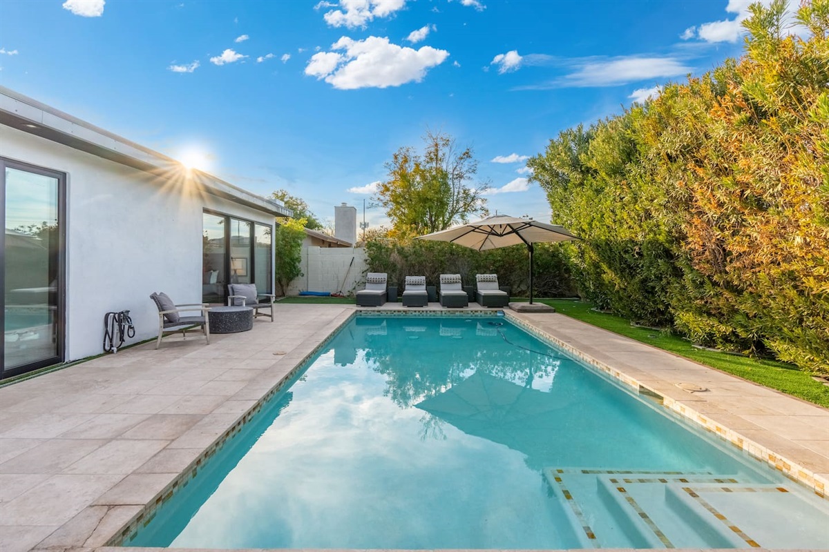 Bask in the glow of the setting sun as it reflects on the pristine pool surface — your own private oasis awaits just outside the bedroom.