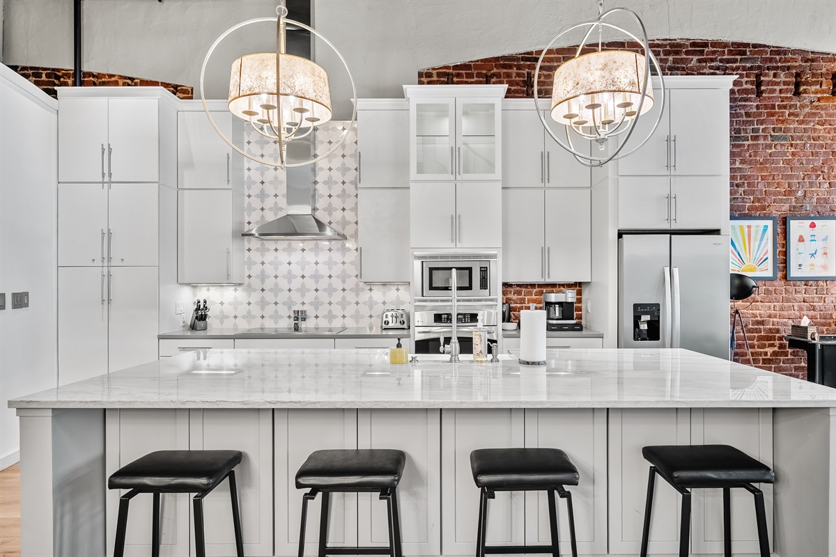 Fully equipped chef’s kitchen with granite countertops and bar seating.