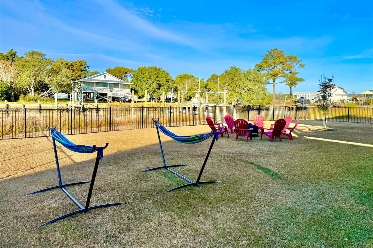 Private backyard dock with boat lift and fillet table, fenced-in backyard, fire pit with Adirondack chairs, hammocks, propane grill, picnic table, outdoor shower, expansive waterfront back deck with table and seating, neighborhood boat ramp and dock