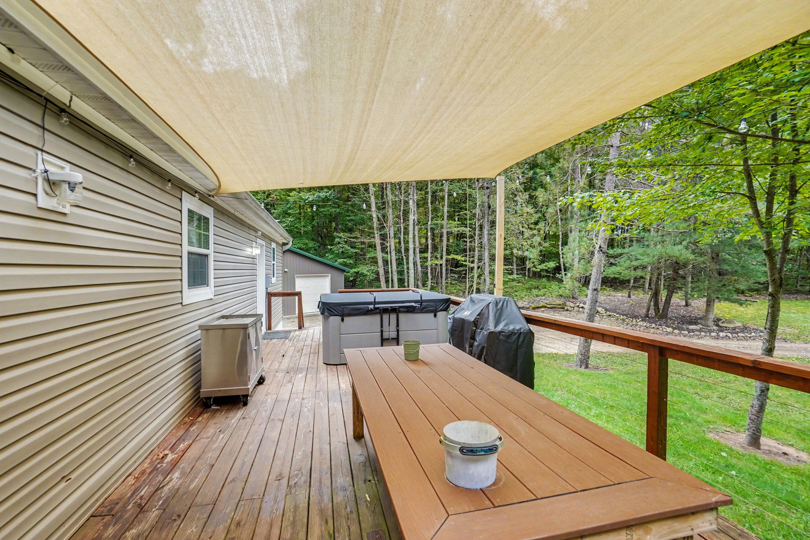 Deck with patio table, gas grill and hot tub.