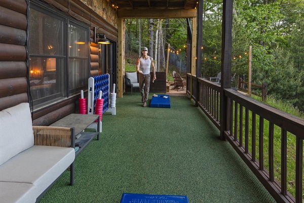 Challenge friends or family to a game of cornhole on the lower deck, surrounded by forest views, with plenty of seating nearby for relaxing between rounds.