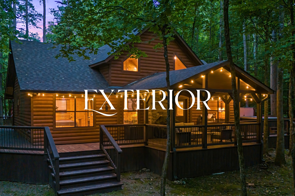 Glowing front view of the cabin at dusk with cozy lighting, welcoming porch, and forest setting.