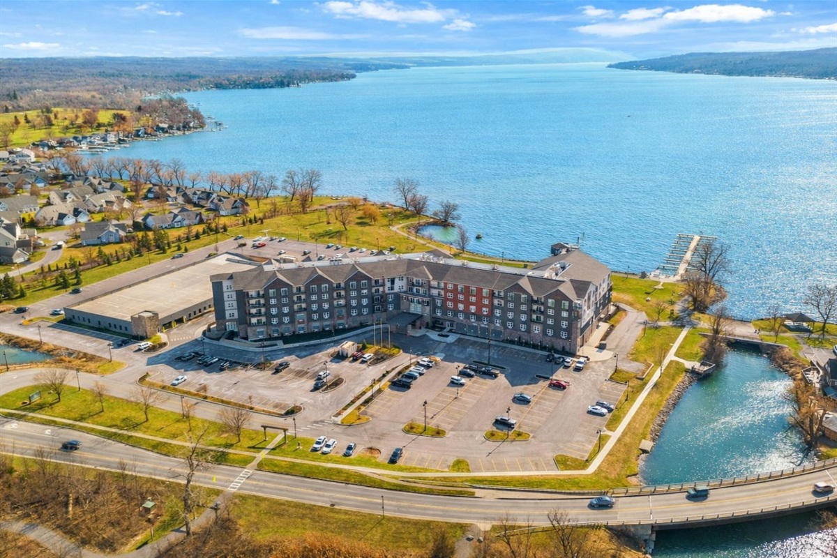 Arial view of lakeside apartment complex with ample parking and scenic views.