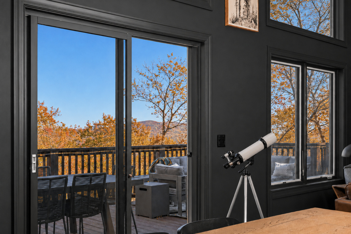 Dining room with sweeping treetop and mountain views, a telescope for taking it all in, and direct access to the deck. In fall, the surrounding canopy glows with gold, orange and red.