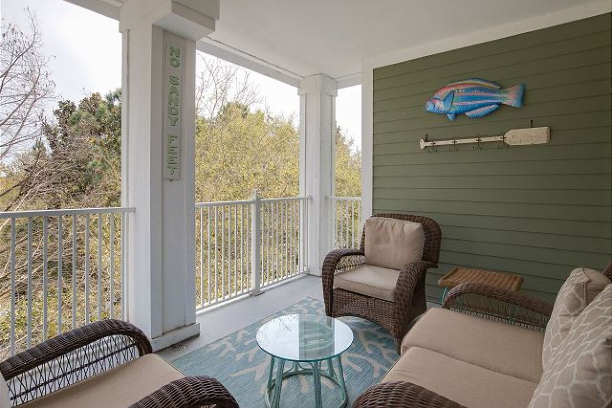 Balcony seating area with wicker furniture and coastal wall art on the fourth floor
