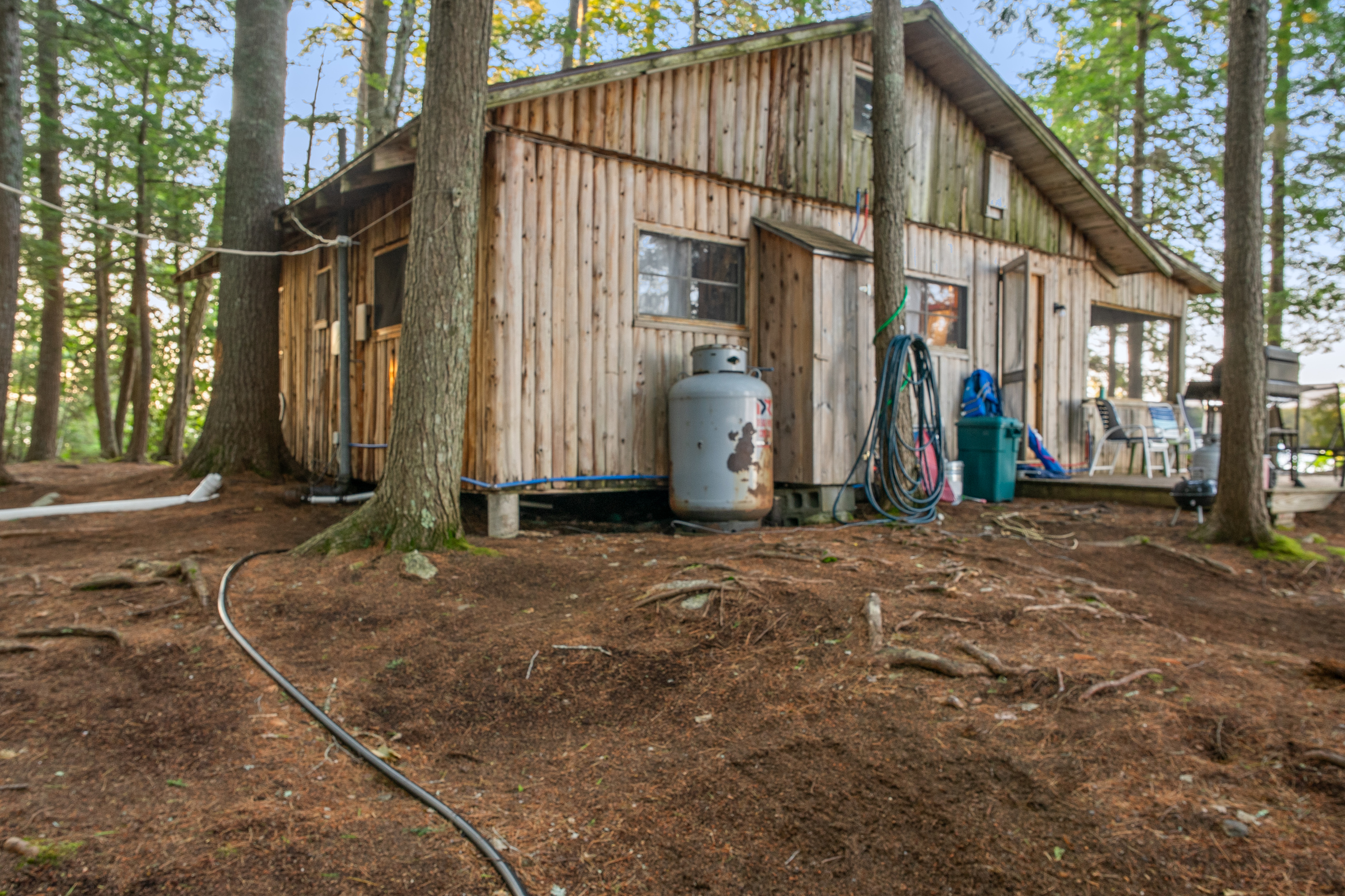 East side of Loonrise Point showing raw camp utilities: exposed PEX water lines, propane tank, and open wiring. Authentic, unvarnished lake living on Beech Hill Pond—ideal for coldwater fishing, with full grocery runs into Ellsworth just 20 mins away.