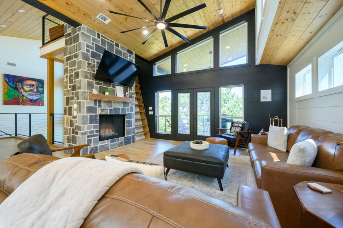 Upper-level living room with a stone fireplace and vaulted wood ceiling.