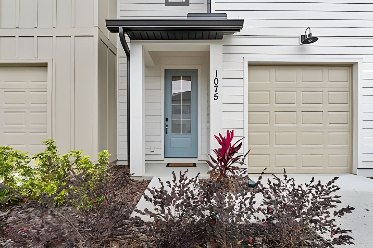 A charming front entrance with a touch of greenery and a cozy porch. 
