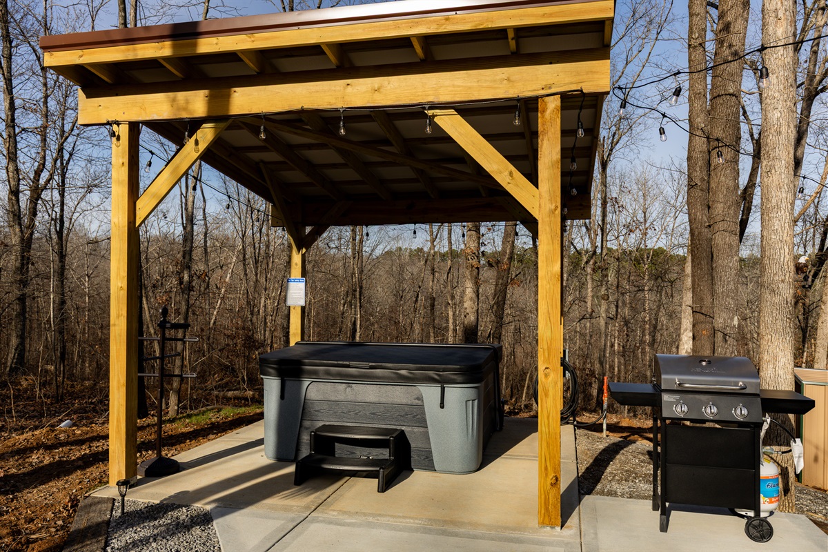Relax year-round in your private, covered hot tub under the pavilion—complete with string lights and just steps from the grill and fire pit, all surrounded by peaceful forest views.