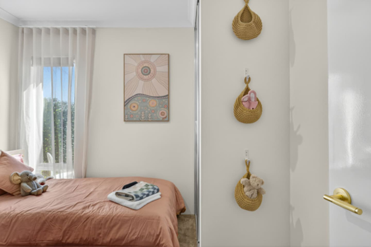 Kid-friendly twin room with soft toys, hanging storage baskets and fresh towels ready on the bed