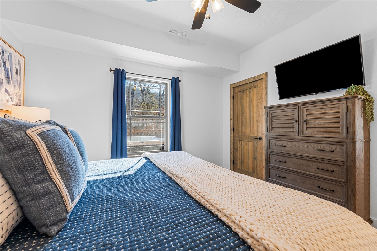 Spacious bedroom view featuring a dresser and TV for added convenience.