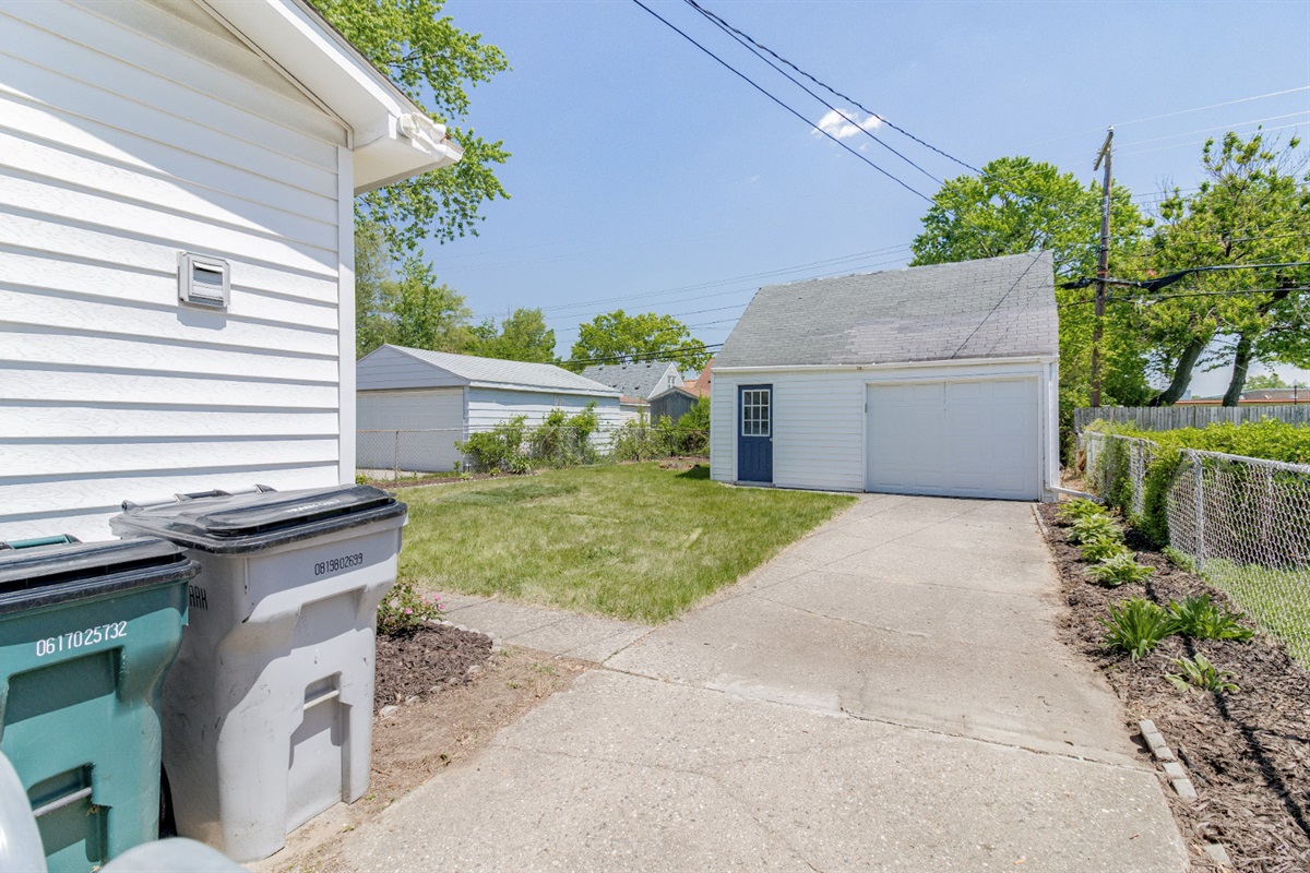 Spacious backyard with a detached garage, long driveway, and plenty of green space—perfect for parking and outdoor activities.