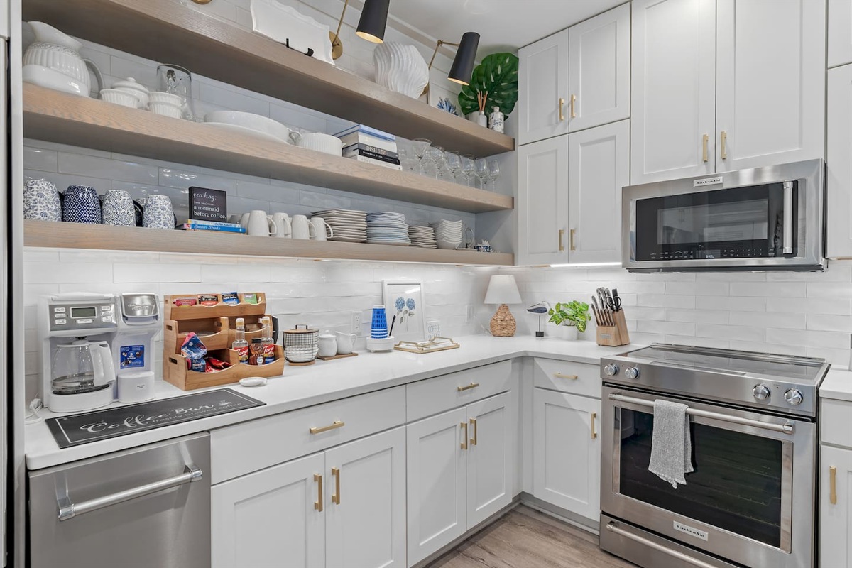 Fully stocked kitchen with KitchenAid ice maker, stove, oven, microwave & coffee/tea bar.