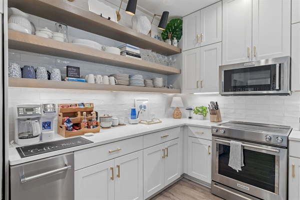 Fully stocked kitchen with KitchenAid ice maker, stove, oven, microwave & coffee/tea bar.