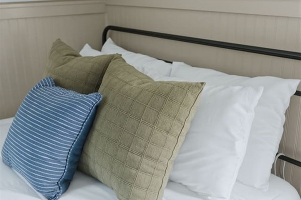 Detailed view of the bed featuring comfortable pillows, crisp white linens, and charming bird-pattern accent wall.