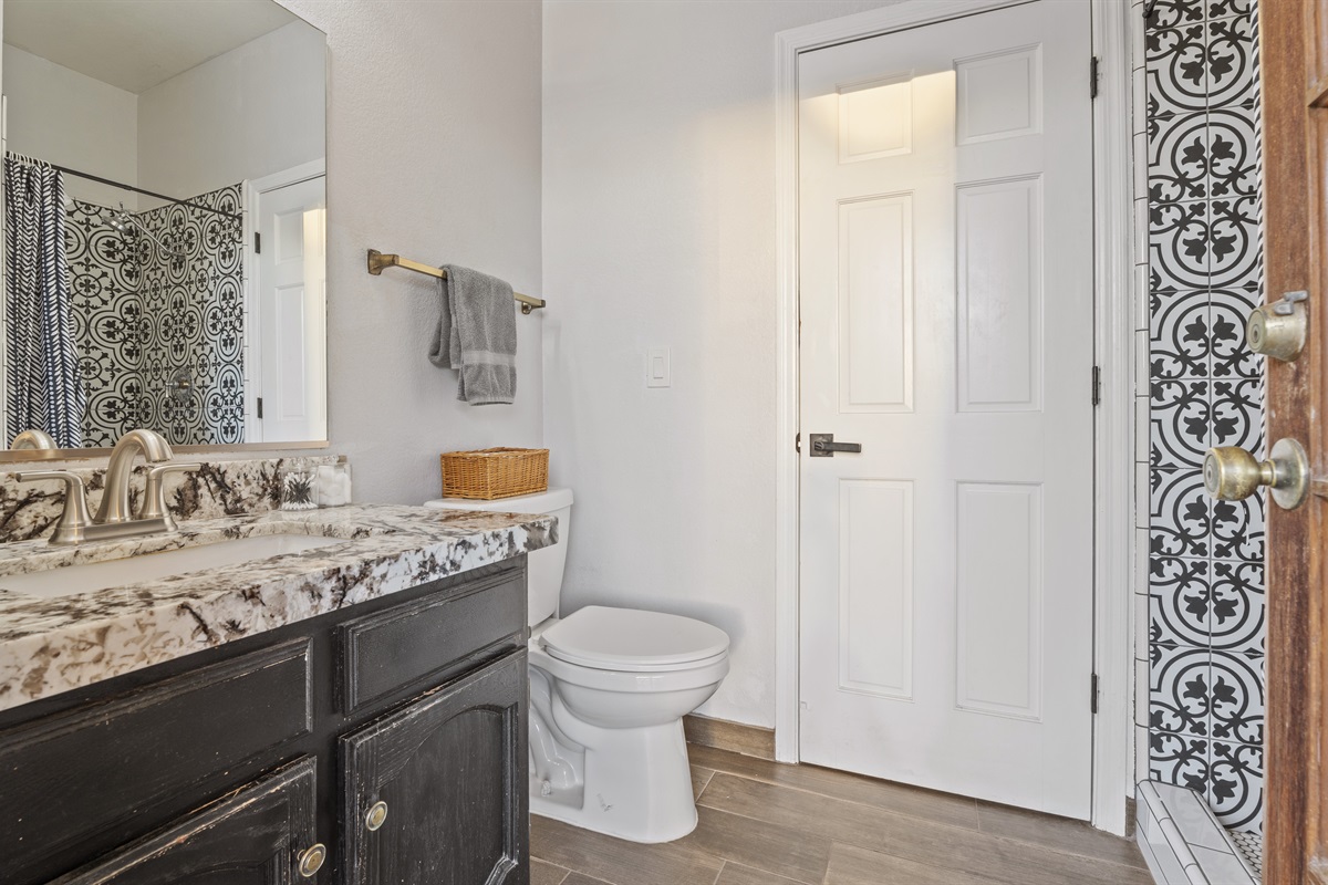 Elevate your stay with this chic bathroom featuring custom tile, a stone countertop, and a spa-style shower experience.