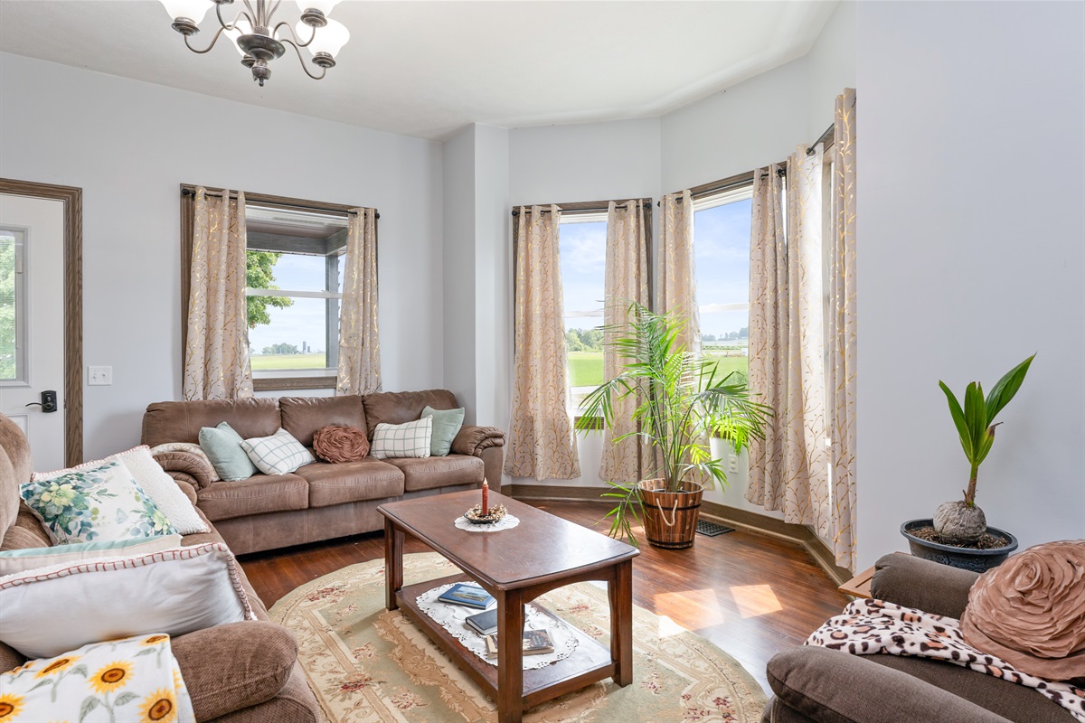 Bright and inviting living room with bay windows, cozy seating, and natural light—perfect for relaxing with a view.