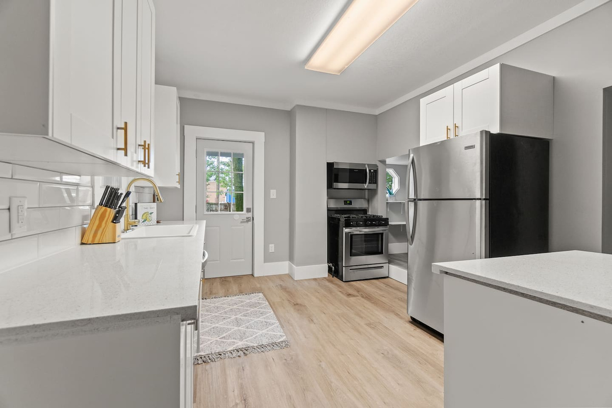 Full kitchen with stainless appliances, white cabinets, and back door access.