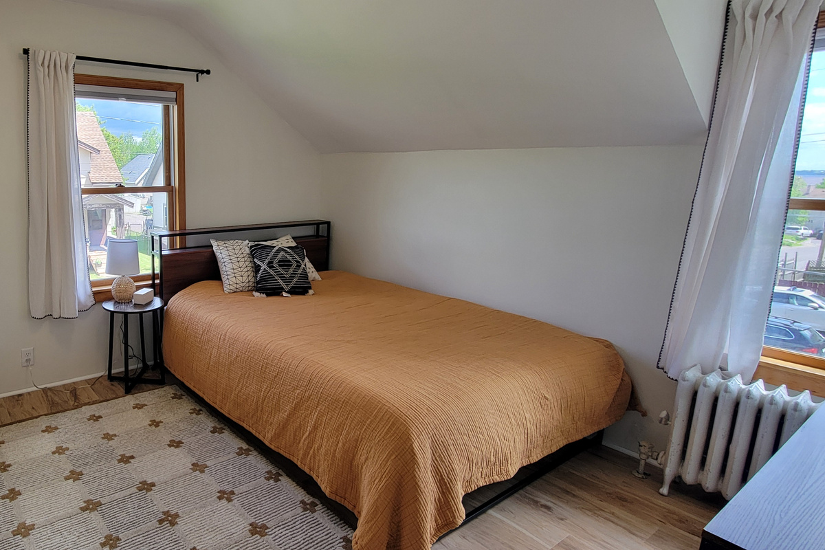 Second bedroom with queen bed and pull-out twin trundle — flexible sleeping space for families or groups.