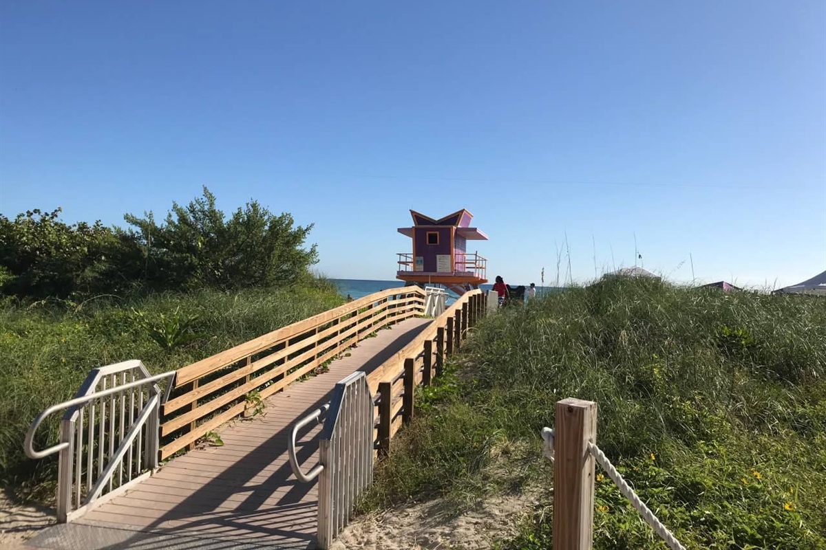 Wooden boardwalk through protected dunes to the beach, art deco lifeguard stand ahead