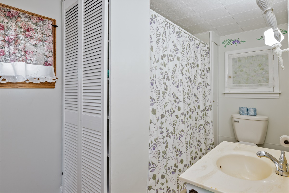Clean, cheerful full bathroom with floral details and all the essentials for a comfortable stay.