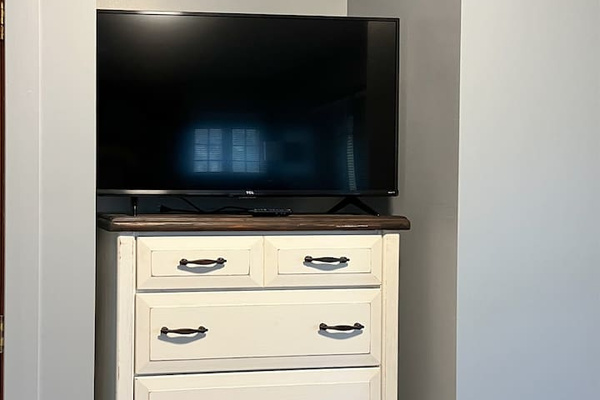 Stylish bedroom featuring a modern cabinet and a widescreen TV mounted on a sleek countertop—designed for contemporary comfort and functionality, offering a perfect balance of elegance and relaxation in a cozy space