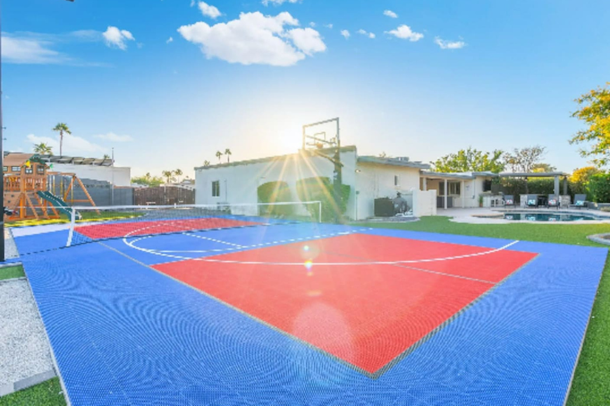 Sunlight streams across the court in this golden-hour shot, framed by the home and mountains beyond.