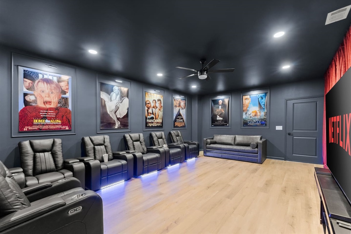 Private home theater with a large screen, plush seating, and dramatic red curtains—perfect for an immersive movie experience.