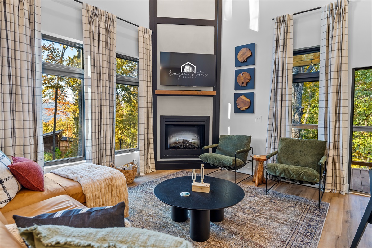 Floor-to-ceiling windows frame the mountains and trees