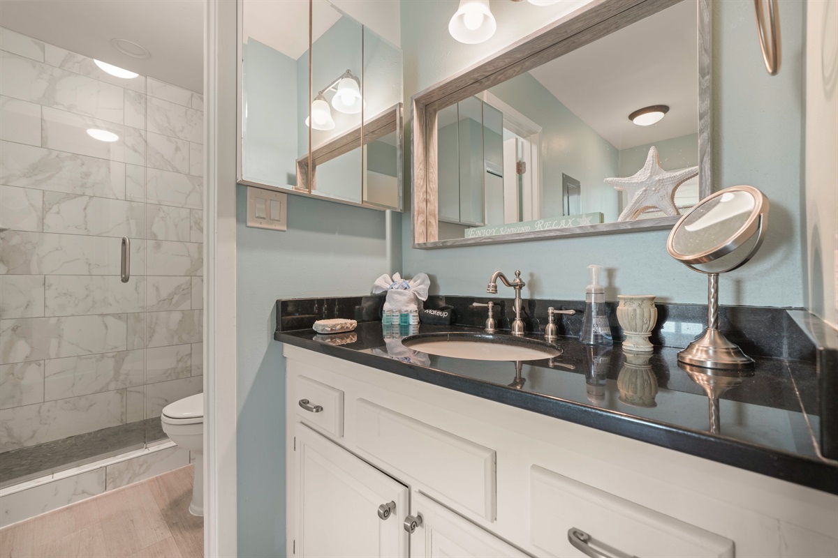 Spa-worthy shower in the master bath. Marble tile walls, pebble stone floor, and a frameless glass enclosure — a cut above most rentals.