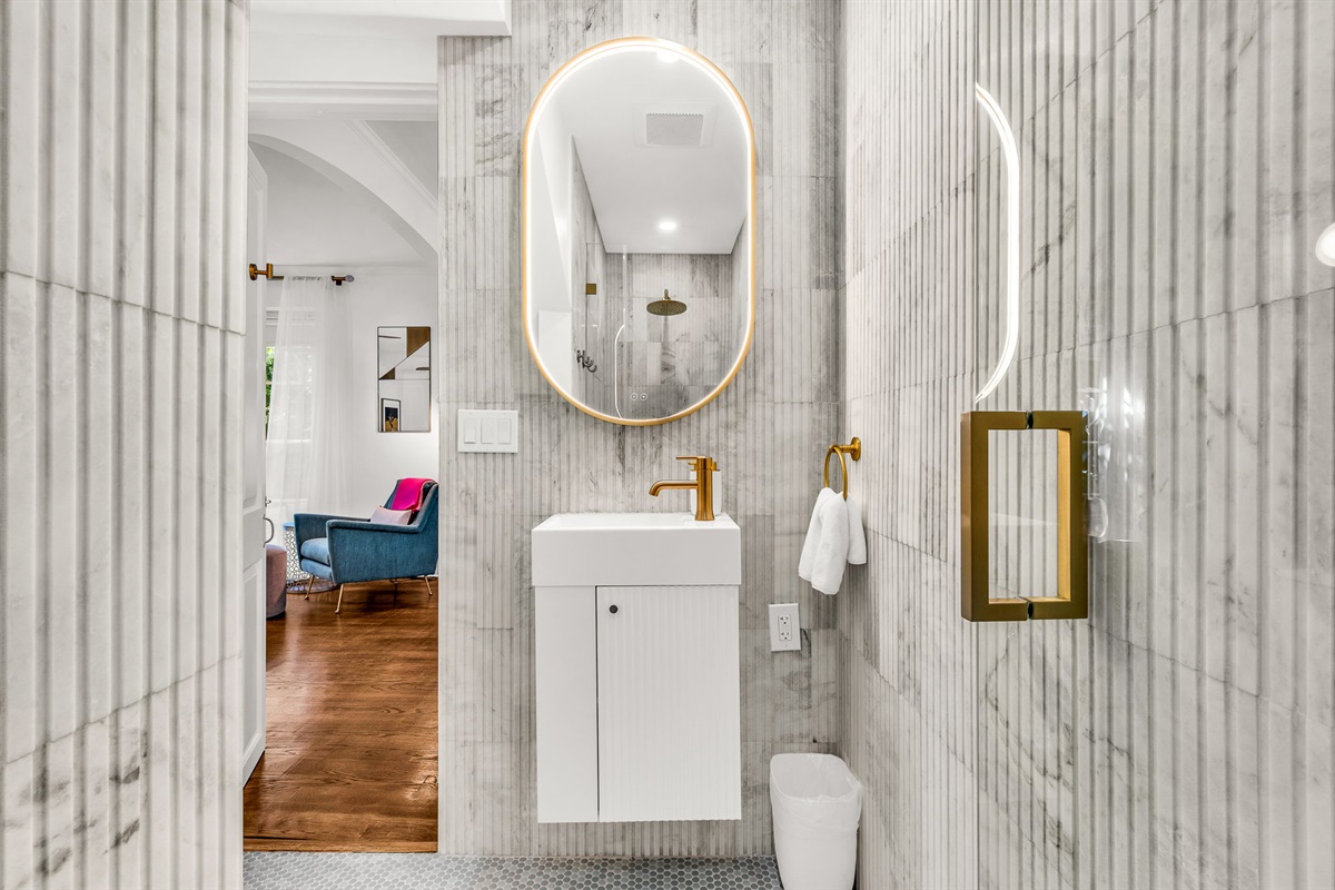 Full Bathroom #3: Discreetly located off the dining room, this newly built guest bathroom showcases floor-to-ceiling fluted marble, a spa-inspired shower, floating vanity, and an elegant make-up bar for a true resort feel.