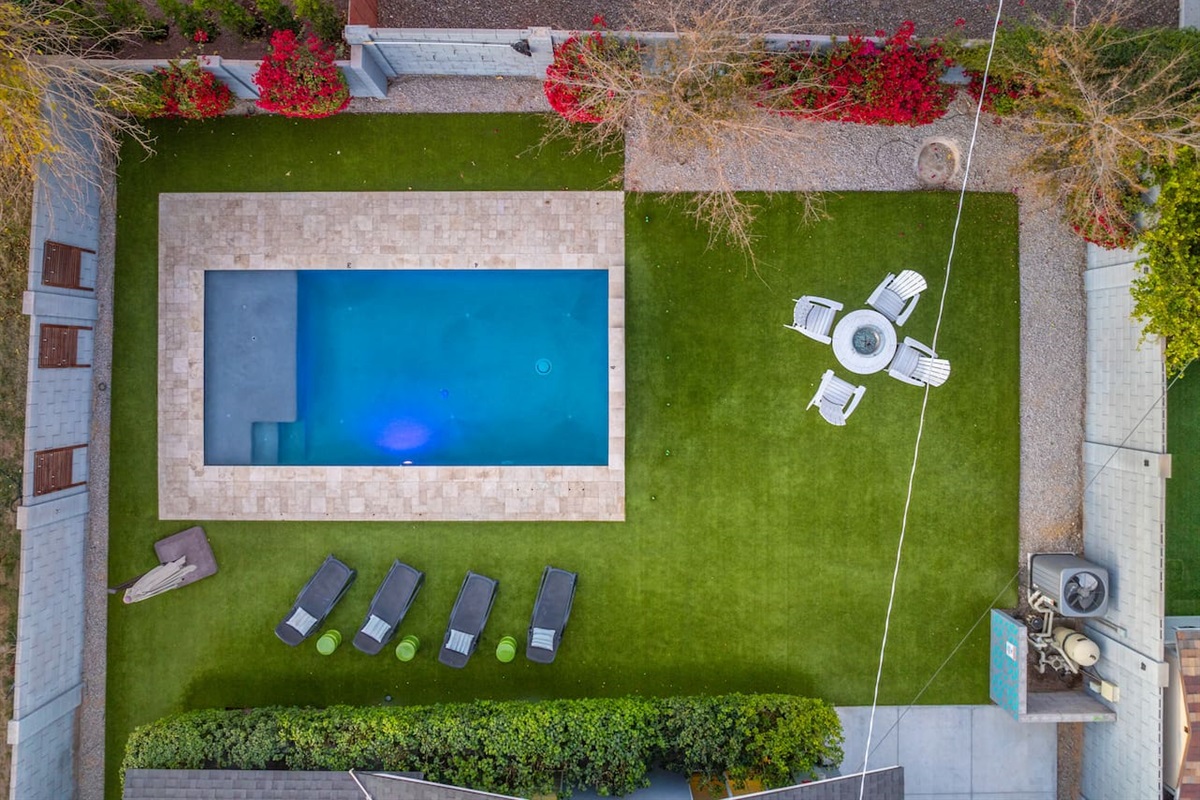 Aerial view of the backyard, capturing the expansive layout with the pool, seating areas, and surrounding greenery for a complete perspective.