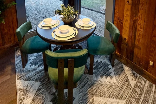 Dining table set against rich wood paneling and vibrant greenery.
