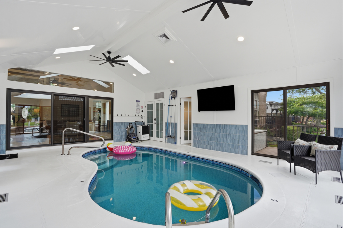 Year-round fun awaits in this stunning indoor heated pool room, featuring vaulted ceilings, skylights, abundant natural light, and a spacious resort-style design perfect for relaxing, swimming, and creating unforgettable memories with family and friends.