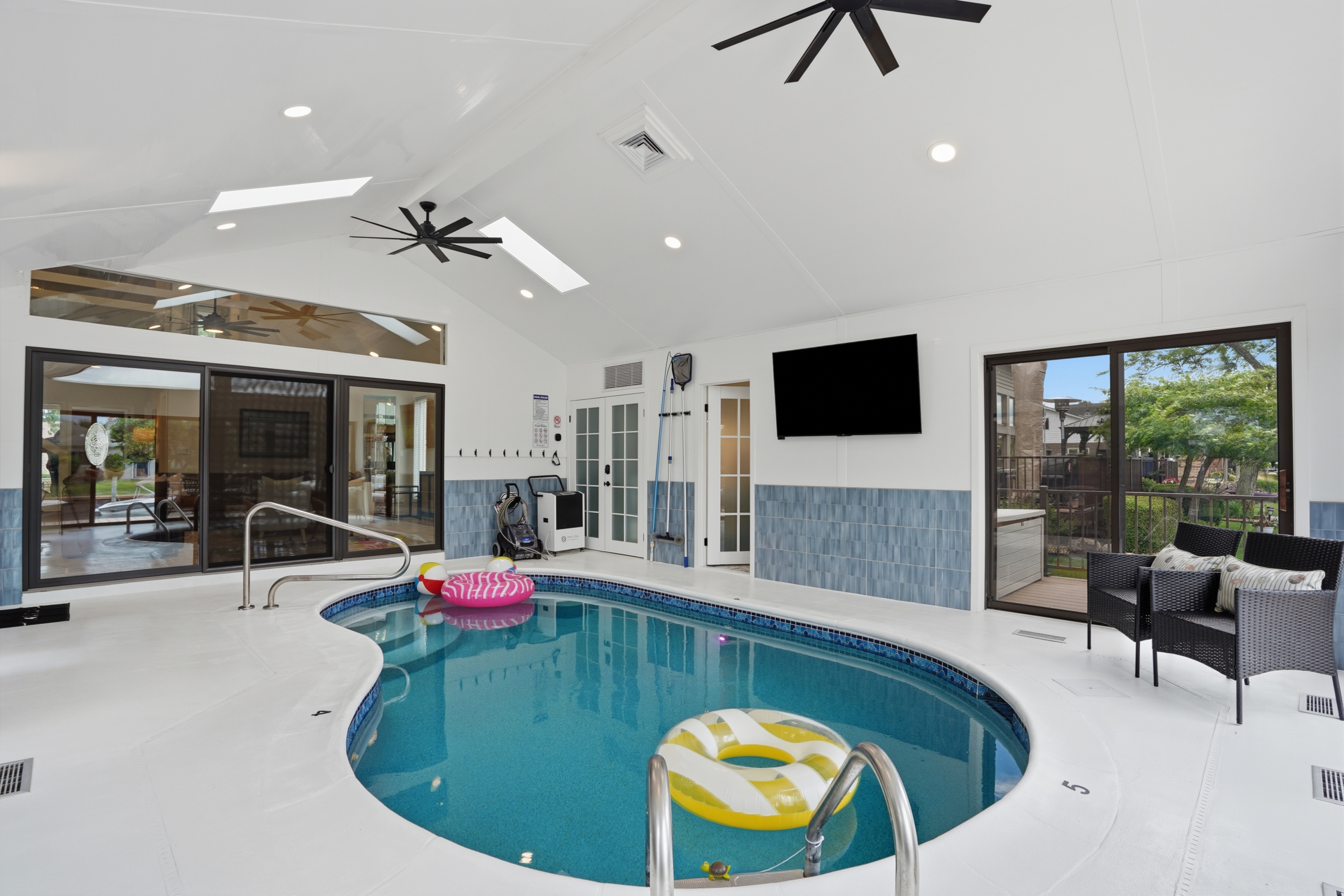 Year-round fun awaits in this stunning indoor heated pool room, featuring vaulted ceilings, skylights, abundant natural light, and a spacious resort-style design perfect for relaxing, swimming, and creating unforgettable memories with family and friends.