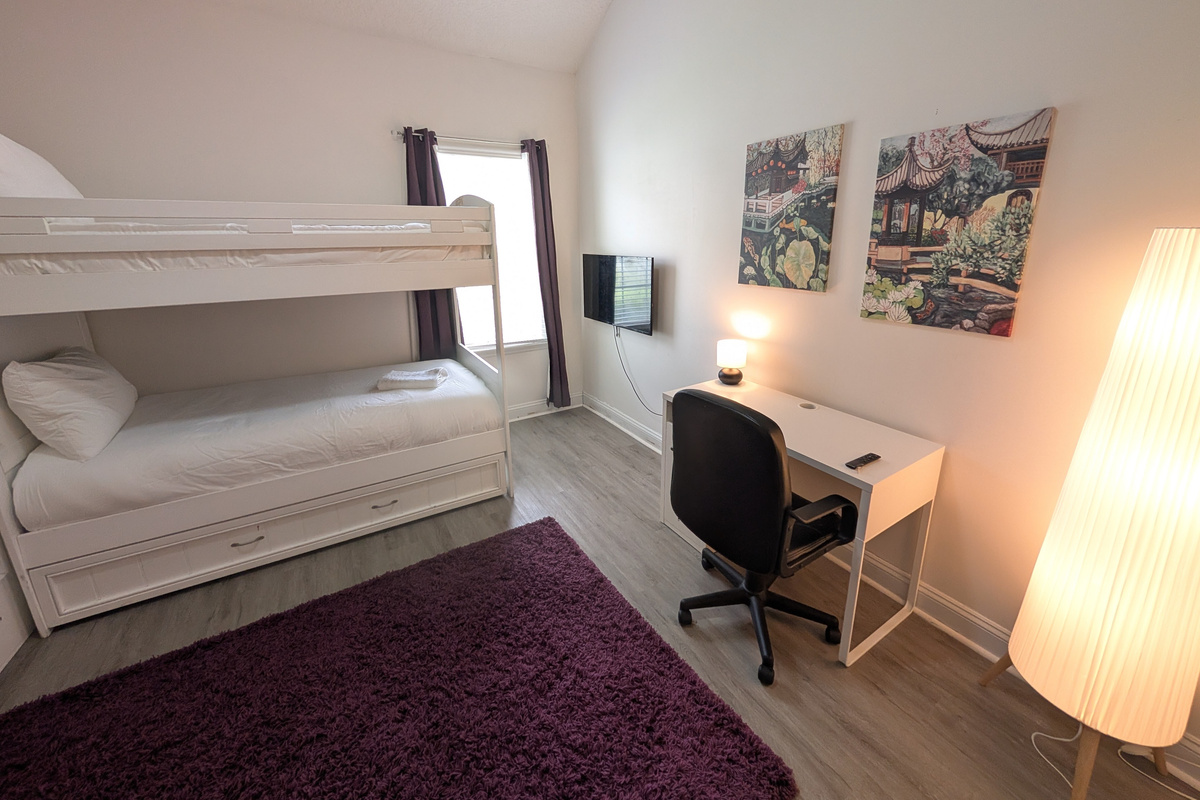 A comfortable bunk-room setup with plenty of open floor space and a dedicated desk for work or school.
