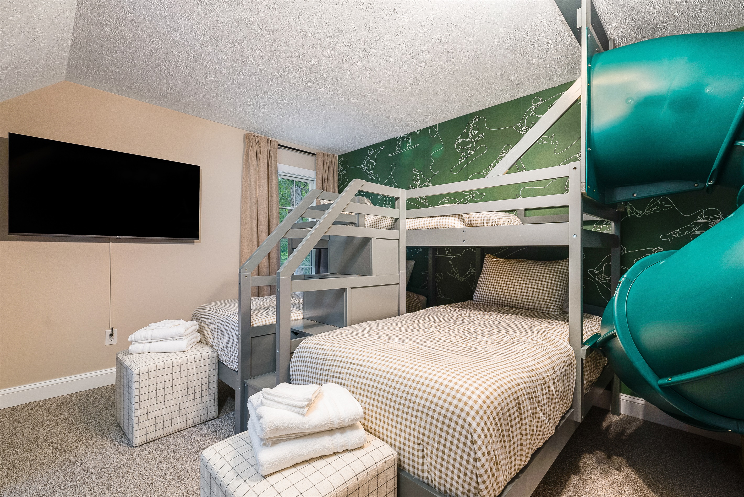 Bunks, slide, TV, and whimsical wallpaper—this room is every kid’s dream vacation.