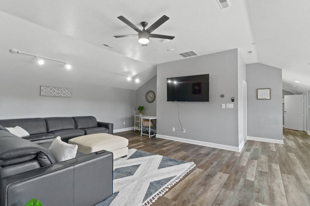 Spacious living area with a plush couch, flat-screen TV, and a soft area rug, creating a perfect space for relaxation and entertainment.
