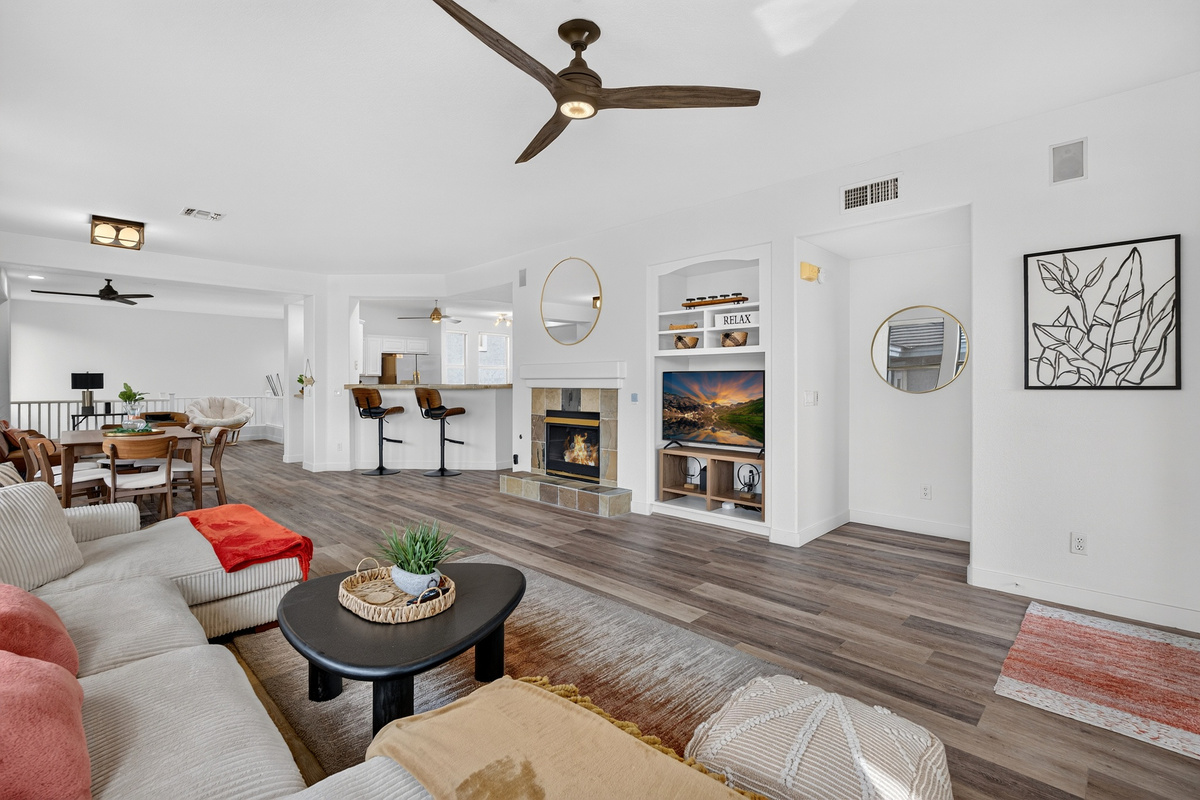 Open living area with comfortable sectional seating, TV, fireplace, and easy flow to the dining and kitchen spaces.