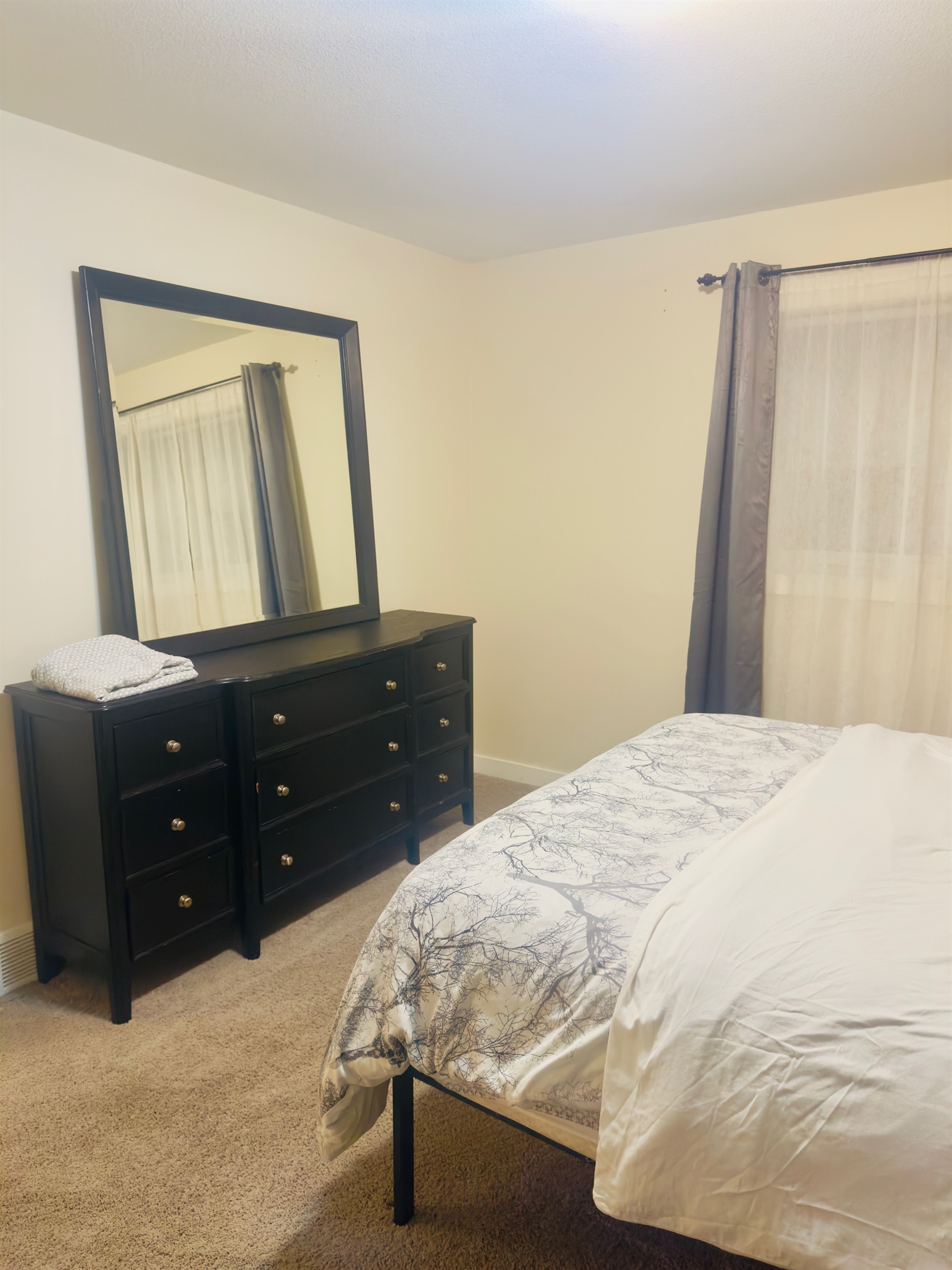 Bedroom with comfy queen sized bed, dual nightstands, walk in closet and accent chair.