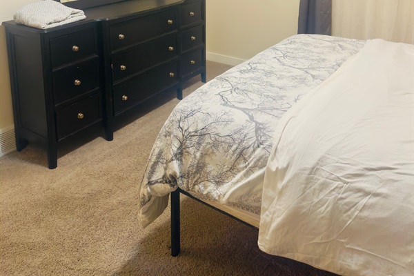 Bedroom with comfy queen sized bed, dual nightstands, walk in closet and accent chair.