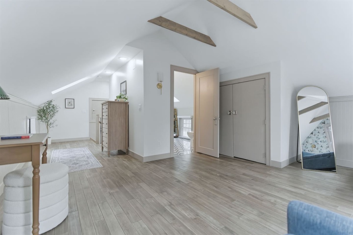 Spacious loft layout with open floor space, dresser storage, full-length mirror, and easy access to the bathroom.