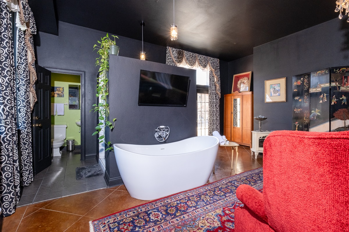 Open-concept layout highlighting the soaking tub, wall-mounted TV, and distinctive design details.