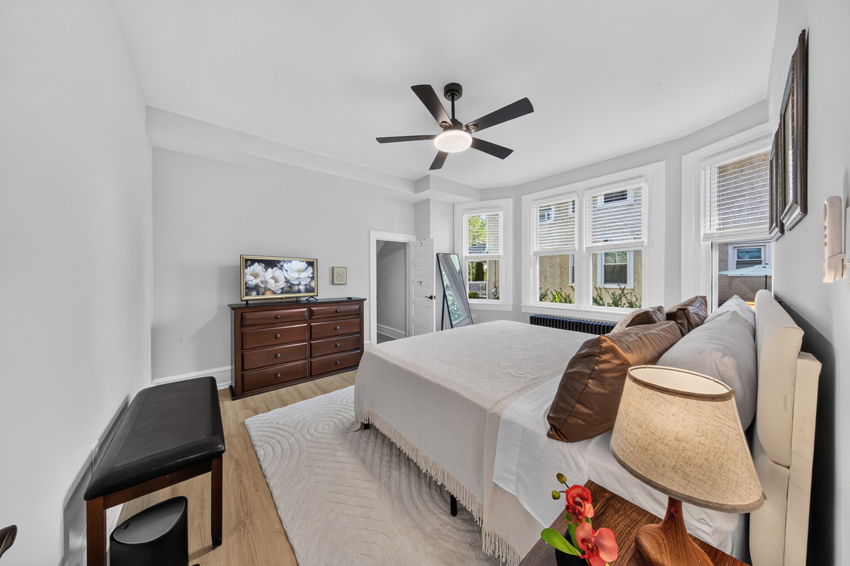 Ample dresser storage, flat-screen smart TV, and bright natural morning light.